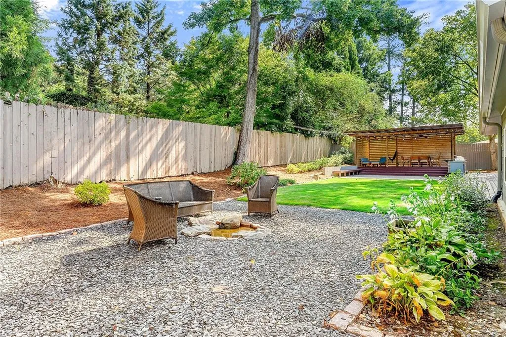 Fenced backyard featuring a patio, a wooden deck, and a fire pit