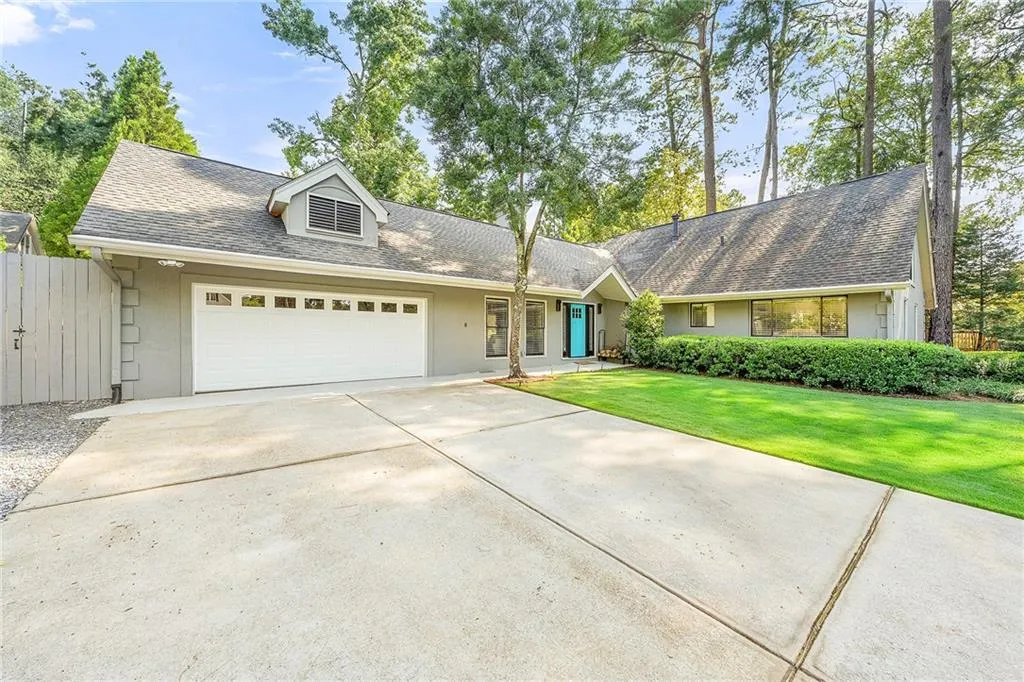 View of front facade with a garage, a shingled roof, concrete driveway, and stucco siding