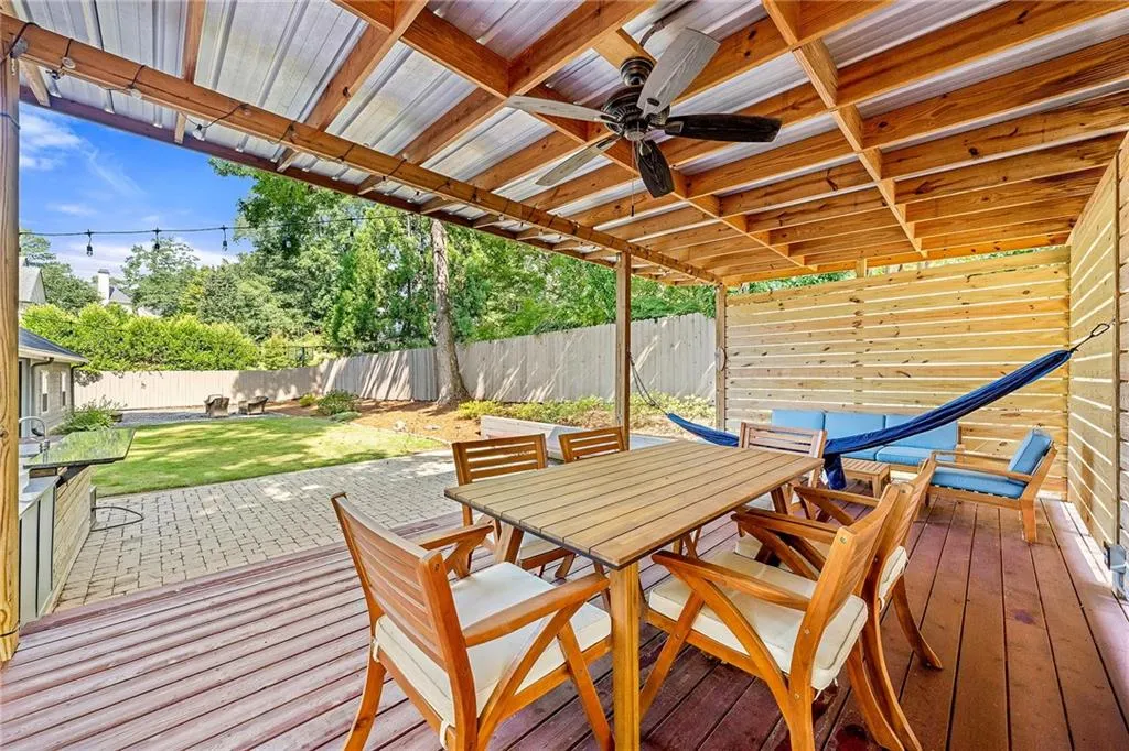 Wooden deck featuring outdoor dining area, a ceiling fan, and a fenced backyard