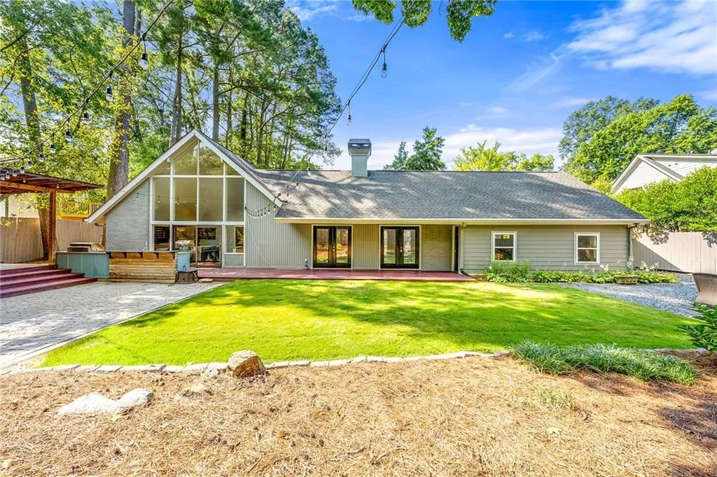 Rear view of property featuring a patio area, a shingled roof, a chimney, and brick siding