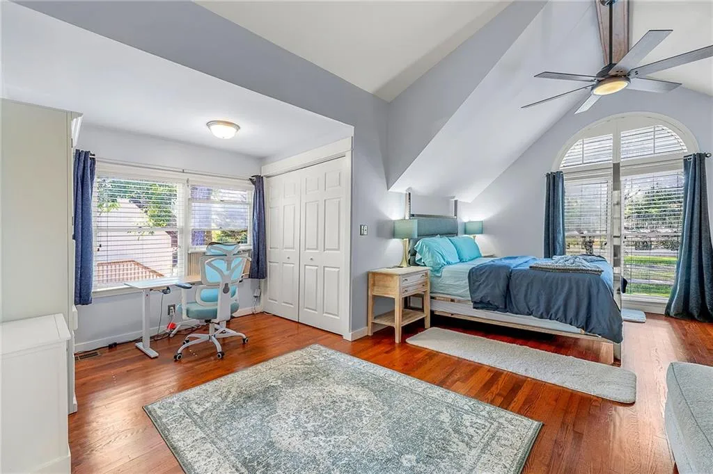 Bedroom with wood finished floors, lofted ceiling, a closet, a ceiling fan, and a desk