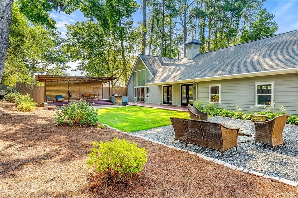 Rear view of property featuring a patio area, a shingled roof, a chimney, and brick siding