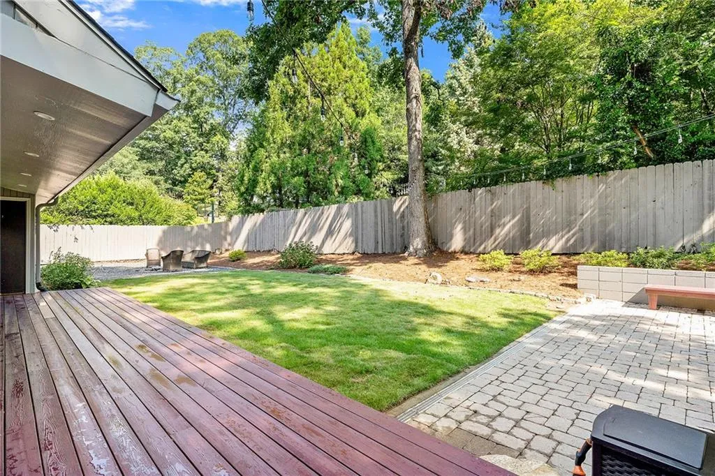 Wooden deck with a patio and a fenced backyard