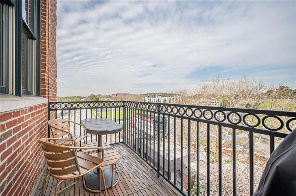 Private outdoor balcony with wood-finish flooring, featuring a decorative black metal railing