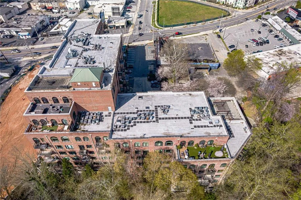 Multi-story brick building featuring arched windows, balconies, and a rooftop terrace with artificial turf