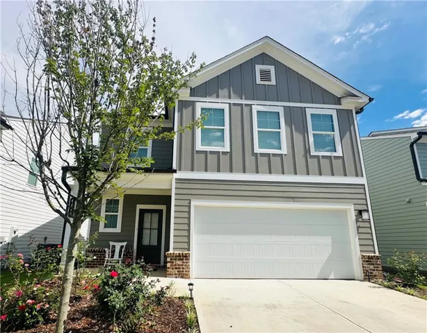 Two-story residence featuring a combination of horizontal and vertical siding, a front-facing garage, and a covered entry porch