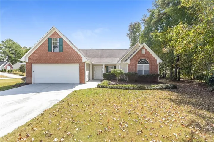 Brick facade with siding accents, attached two-car garage, arched front window, gabled roofline, and established front landscaping