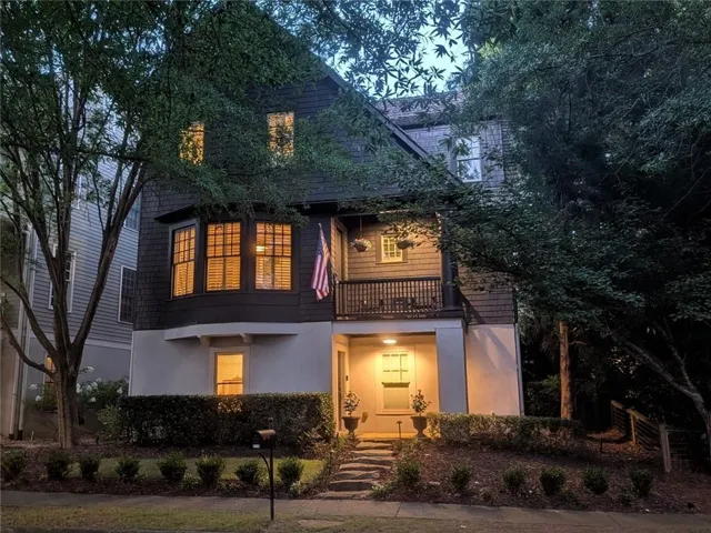 Multi-story residence featuring dark shingle siding, a white foundation, and a covered porch with dark railings