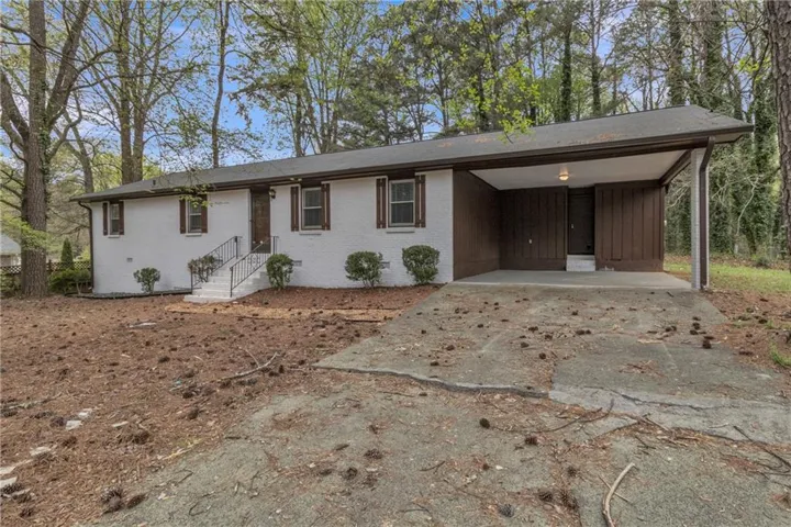 View of front facade featuring concrete driveway, a carport, and brick siding
