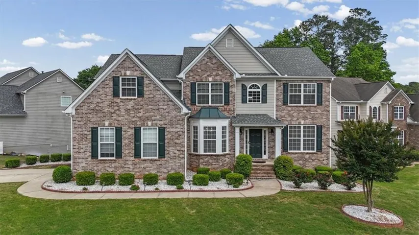 Traditional brick and siding exterior with dark green shutters