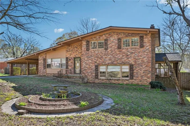 Rear view of house featuring a chimney, brick siding, a carport, and a patio