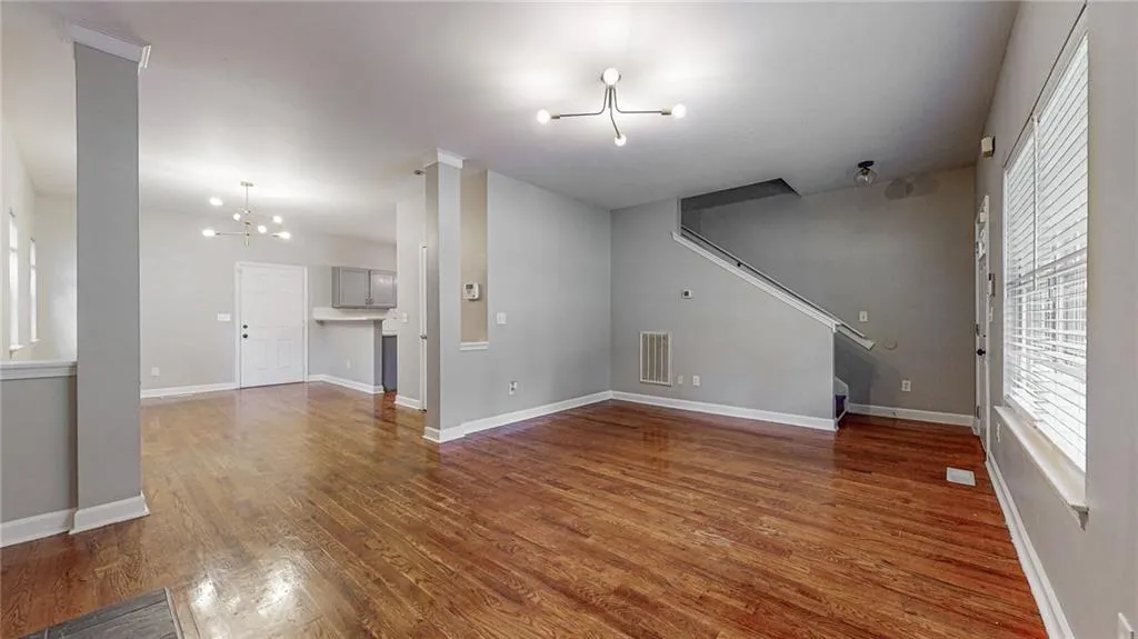 Unfurnished living room featuring a chandelier, dark wood-style flooring, and stairs