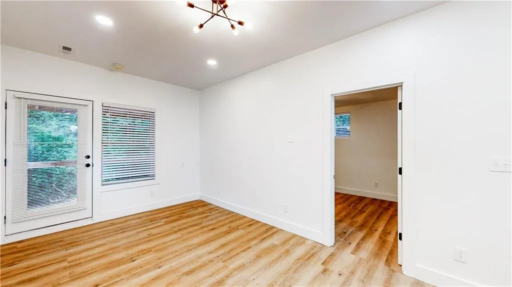 Spare room featuring light wood-style flooring, recessed lighting, and a chandelier
