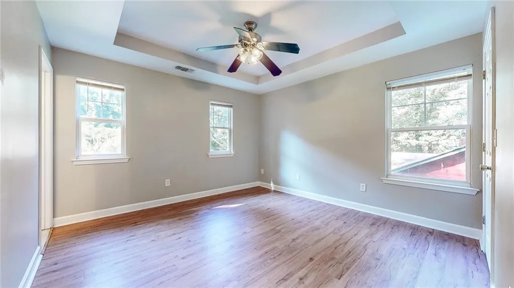 Spare room featuring a tray ceiling, light wood-type flooring, and a ceiling fan