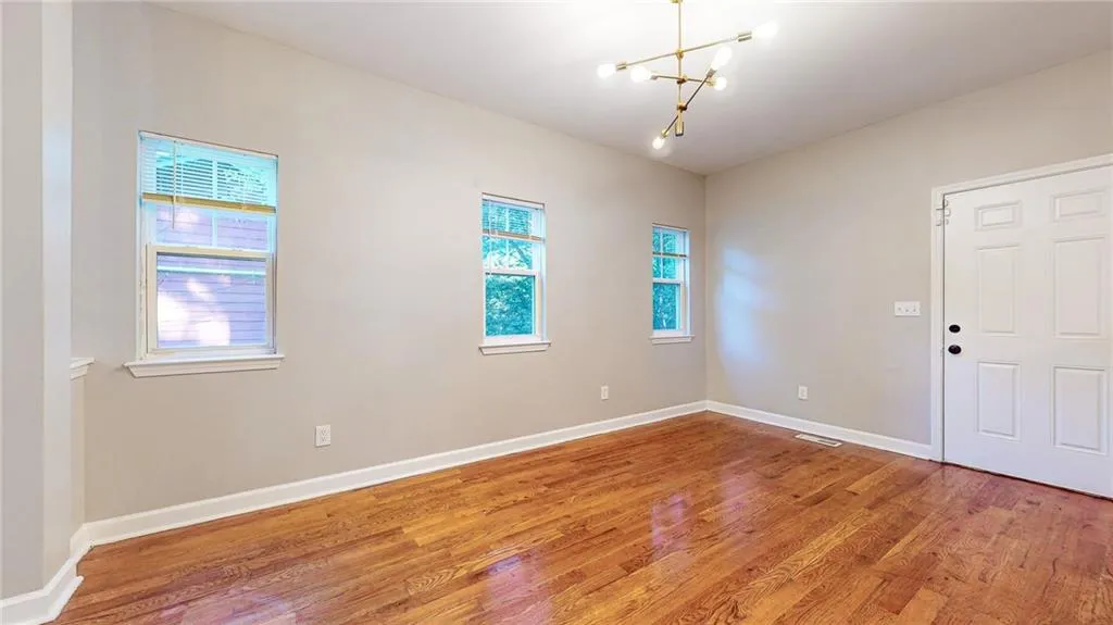 Unfurnished room with a chandelier and light wood-type flooring
