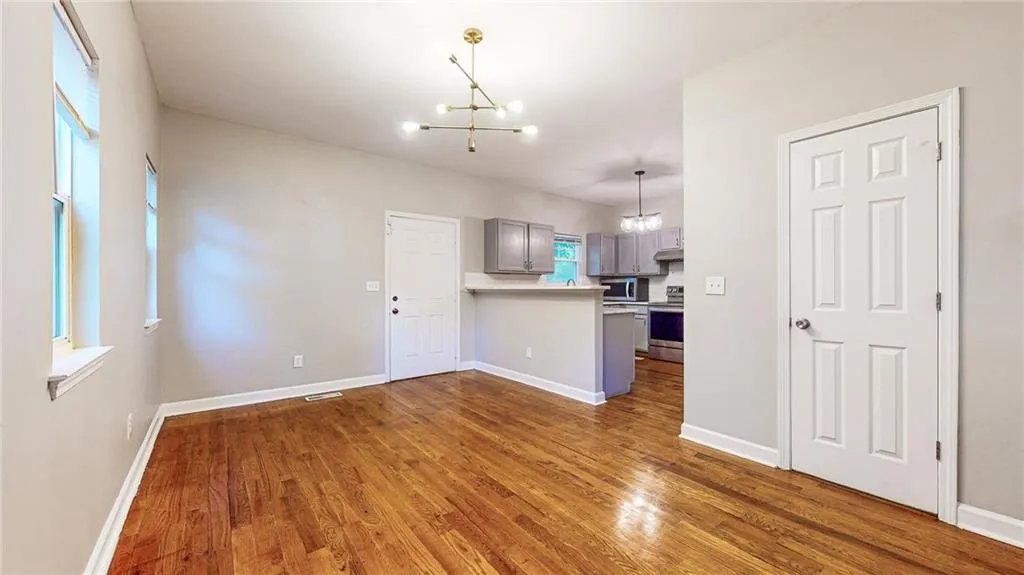 Kitchen featuring gray cabinetry, a chandelier, light countertops, decorative light fixtures, and appliances with stainless steel finishes