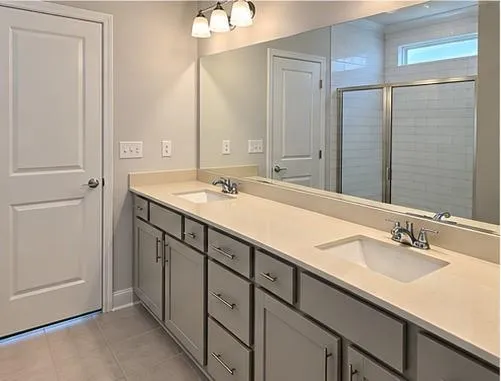 Dual vanity with undermount sinks, integrated countertop, gray cabinetry, and chrome fixtures