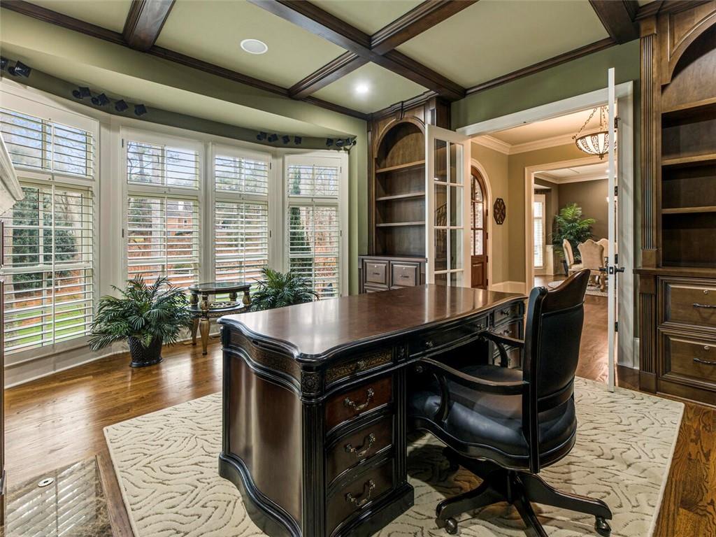 Office with built in cabinetry and coffered ceiling overlooking beautiful exterior grounds