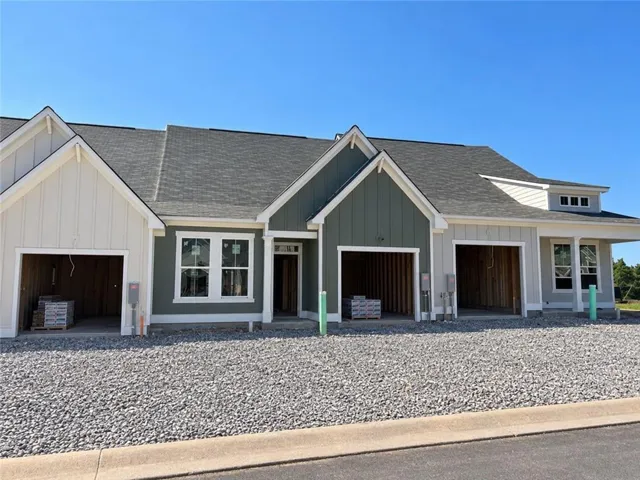 Multi-unit residential structure featuring varied siding, multiple garages, and prominent rooflines
