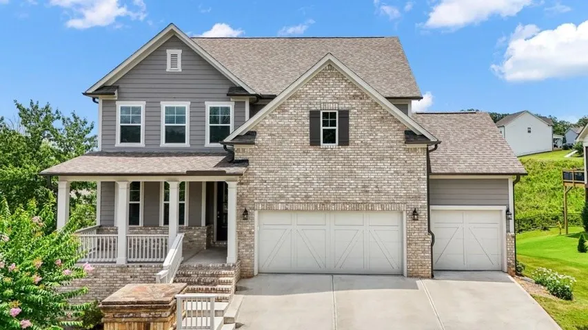 Two-story residence featuring a brick and siding facade with a covered front porch