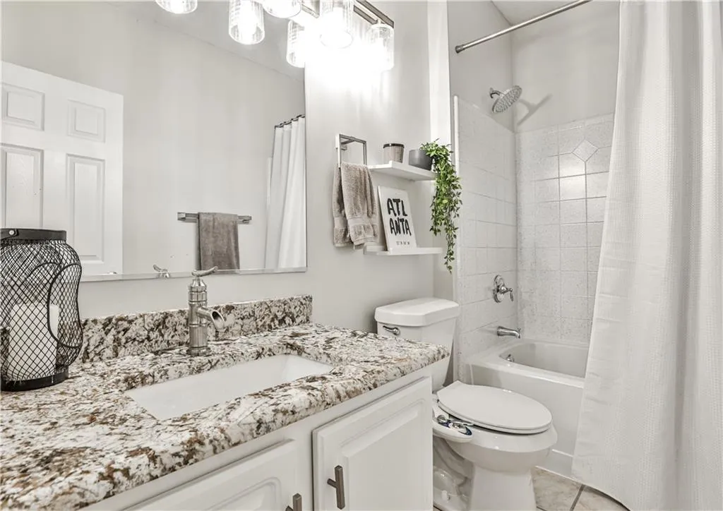 Full bath with shower / bath combo, toilet, tile patterned flooring, and vanity