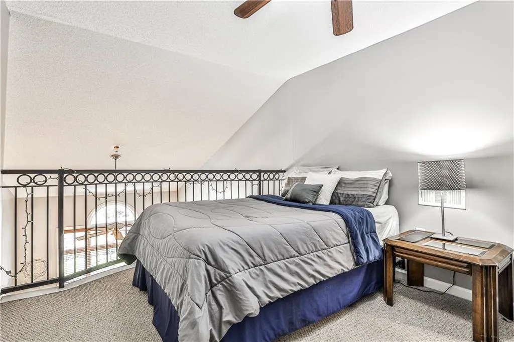 Carpeted bedroom featuring ceiling fan and lofted ceiling
