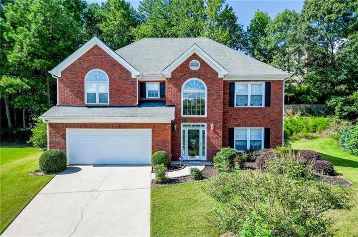 Brick exterior with gabled roof lines, arched window accents, a two-car garage, and a concrete driveway