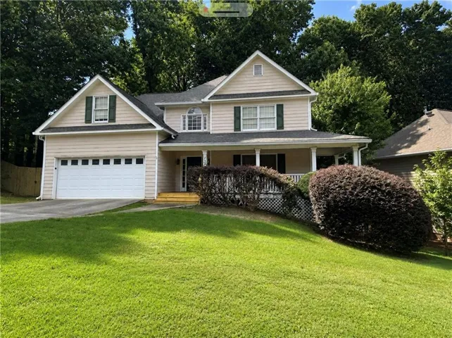 Two-story residence featuring light-colored siding, a covered front porch, and a two-car garage with a panel door