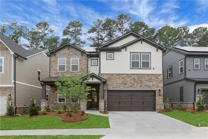 Stone and siding exterior with a covered entry, attached two-car garage, concrete driveway, and manicured landscaping