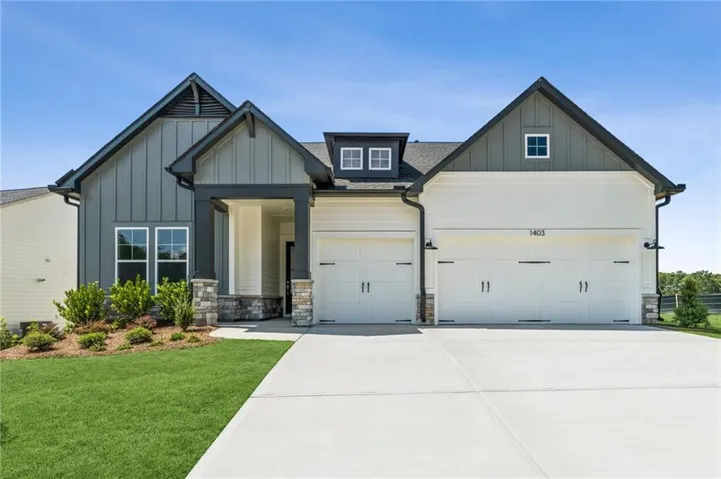 Modern farmhouse exterior with board and batten siding, stone accents, two-car garage, and concrete driveway