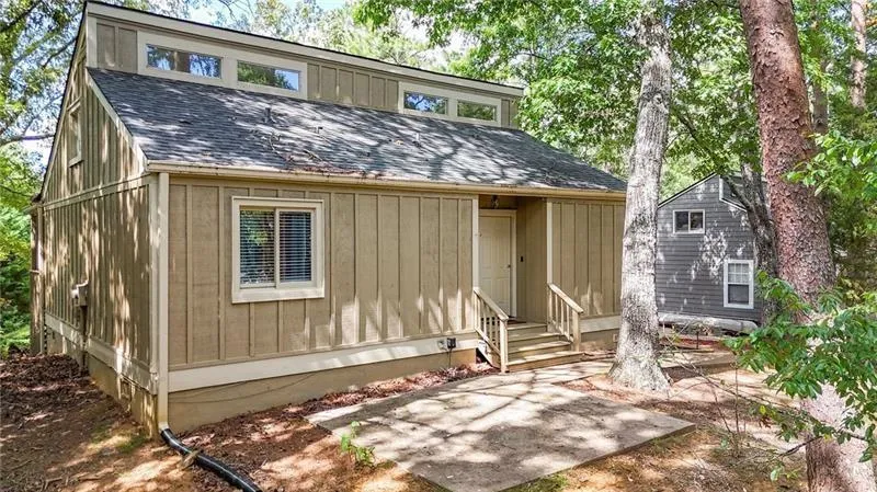 View of front of home featuring a shingled roof, a patio area, and board and batten siding