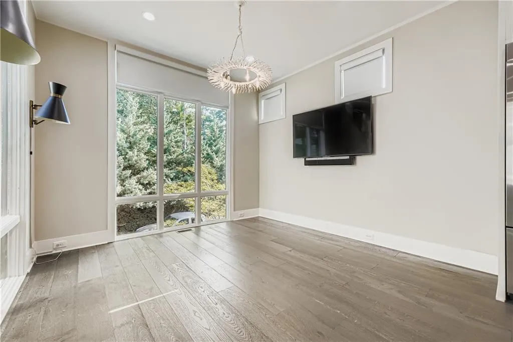 Unfurnished living room with a chandelier, wood finished floors, crown molding, and recessed lighting