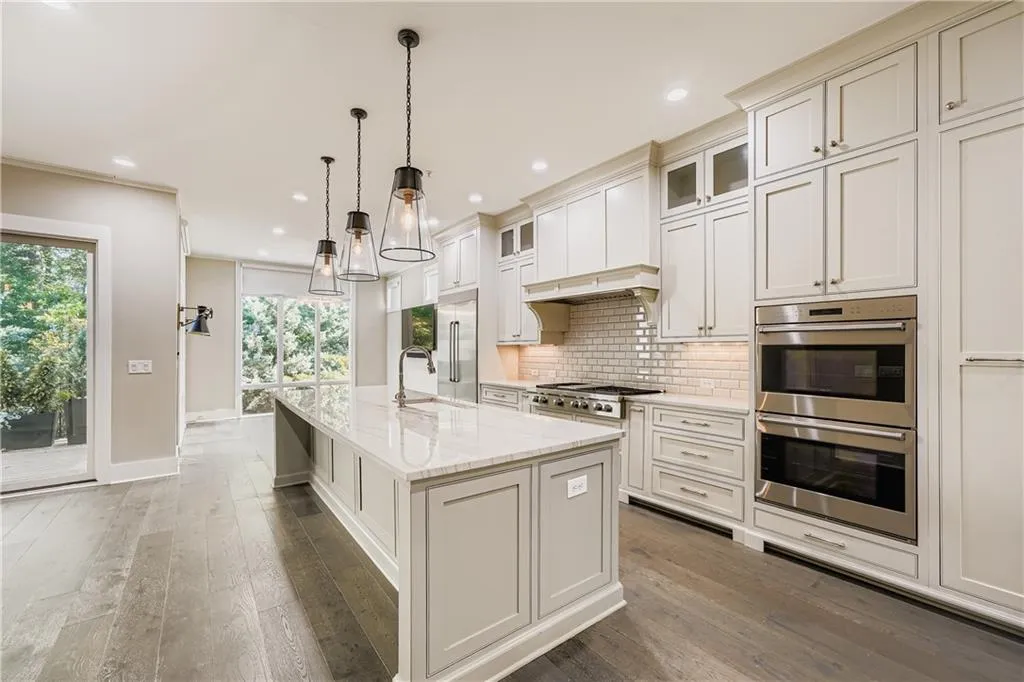Kitchen featuring appliances with stainless steel finishes, decorative backsplash, hardwood / wood-style flooring, a kitchen island with sink, and recessed lighting