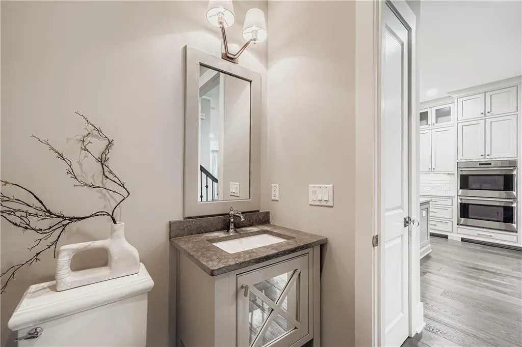 Half bath featuring vanity, wood finished floors, and decorative backsplash