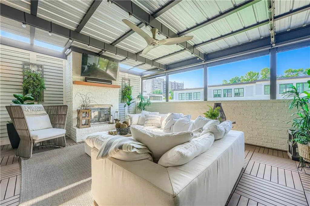 Sunroom featuring a ceiling fan and an outdoor living space with a fireplace
