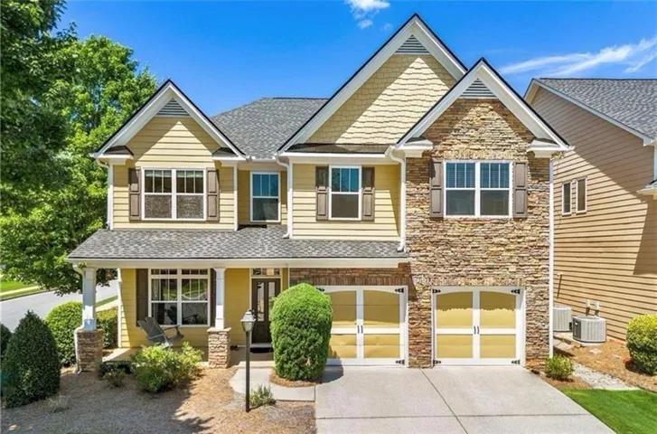 Two-story residence featuring a stone and siding exterior, a covered front porch, and an attached two-car garage