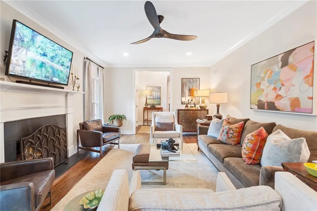 Living area featuring a lit fireplace, wood finished floors, a ceiling fan, recessed lighting, and crown molding
