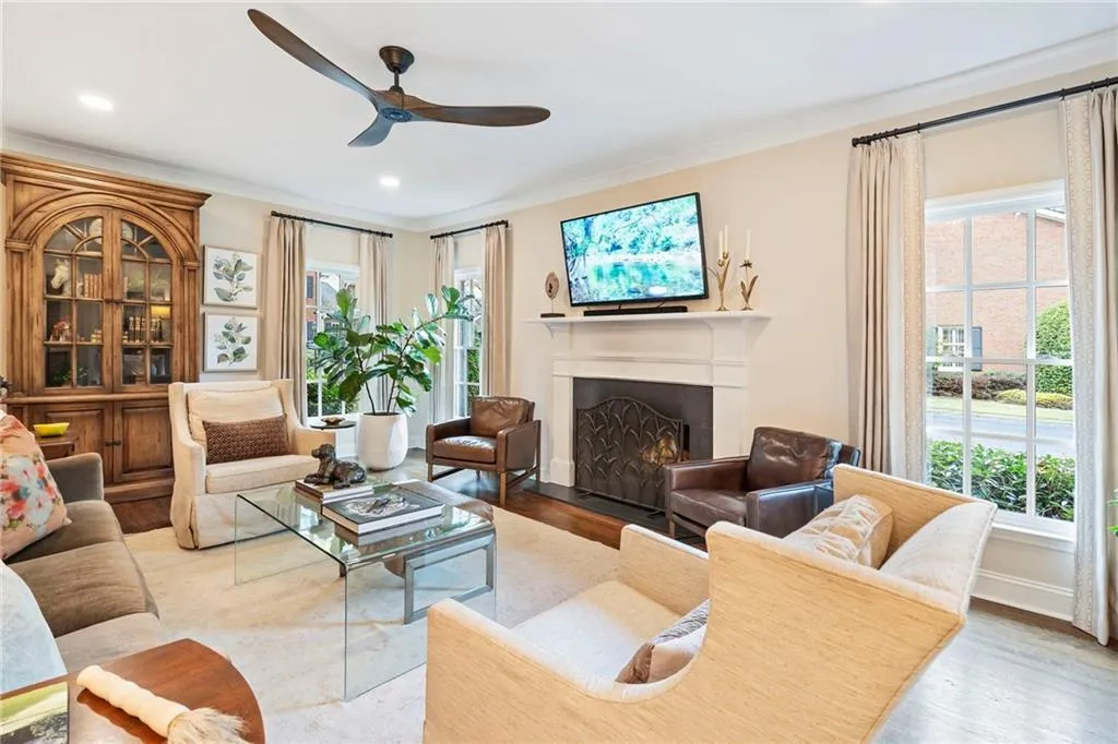 Living room featuring a warm lit fireplace, wood finished floors, ceiling fan, recessed lighting, and crown molding