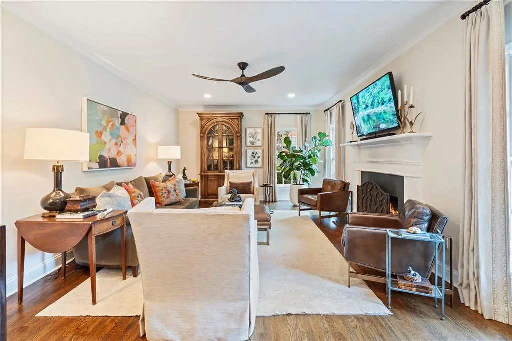 Living room featuring crown molding, a lit fireplace, wood finished floors, ceiling fan, and recessed lighting