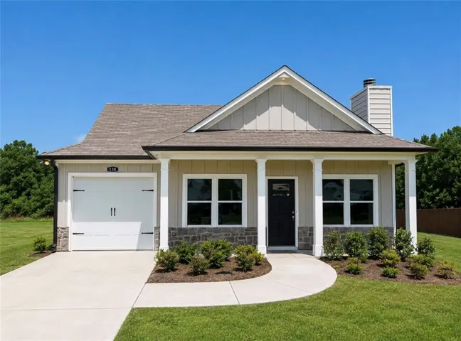Single-story residence featuring a covered front porch with white columns, a dark front door, and a white garage door with decorative hardware
