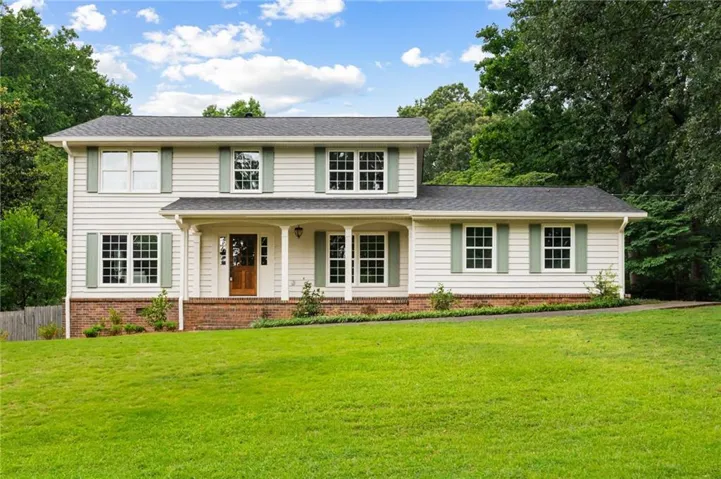 Two-story residence featuring light-colored siding, contrasting green shutters, and a dark shingled roof