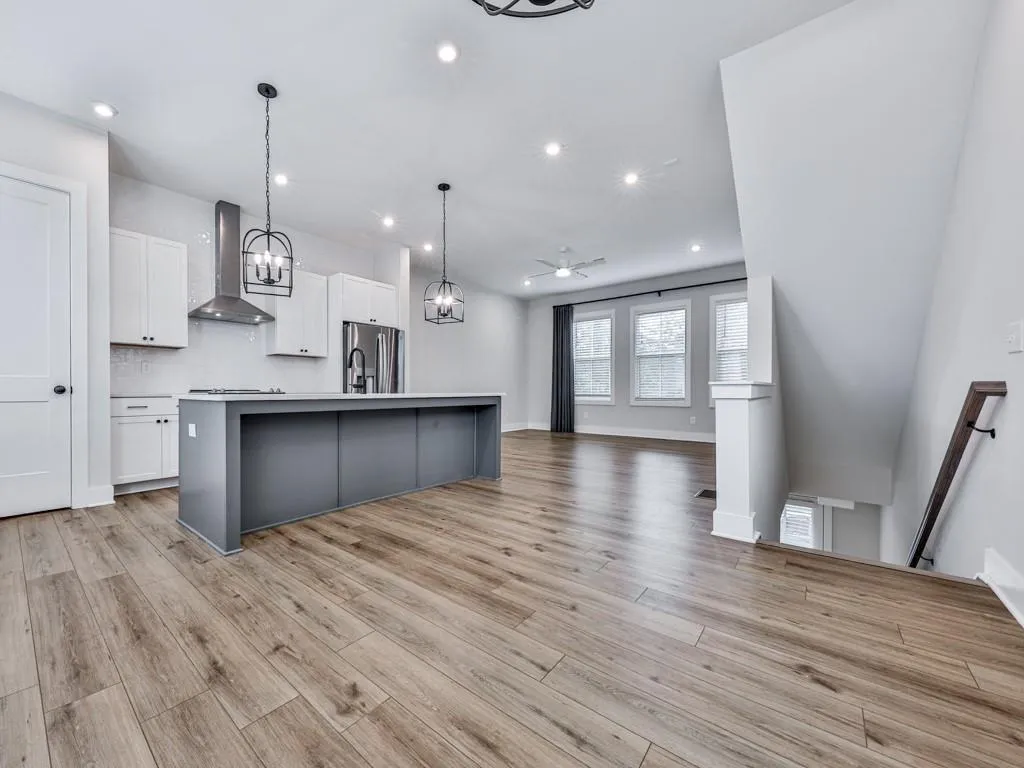 Kitchen featuring white cabinets, recessed lighting, a kitchen island with sink, wall chimney exhaust hood, and tasteful backsplash