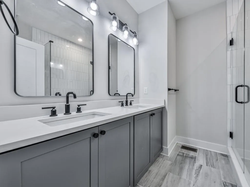 Bathroom featuring a shower stall and double vanity