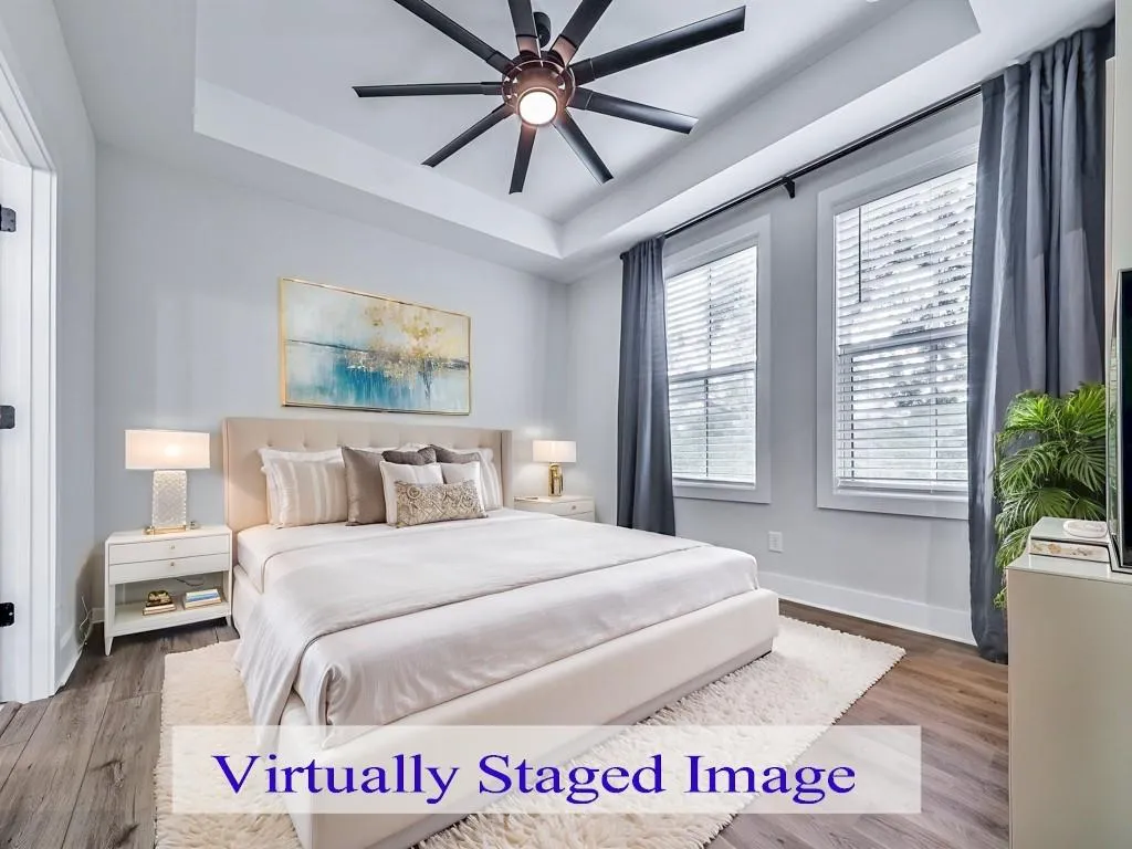 Bedroom featuring a tray ceiling, wood-style floors, and a ceiling fan
