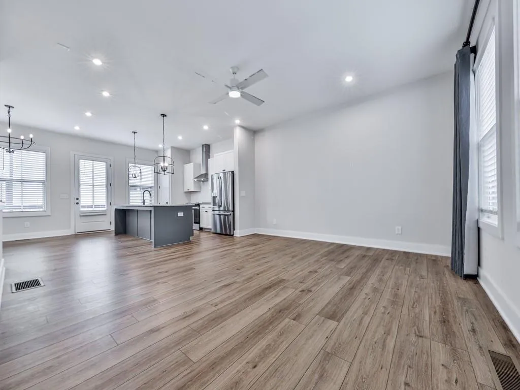 Unfurnished living room with ceiling fan, wood finished floors, a chandelier, and recessed lighting