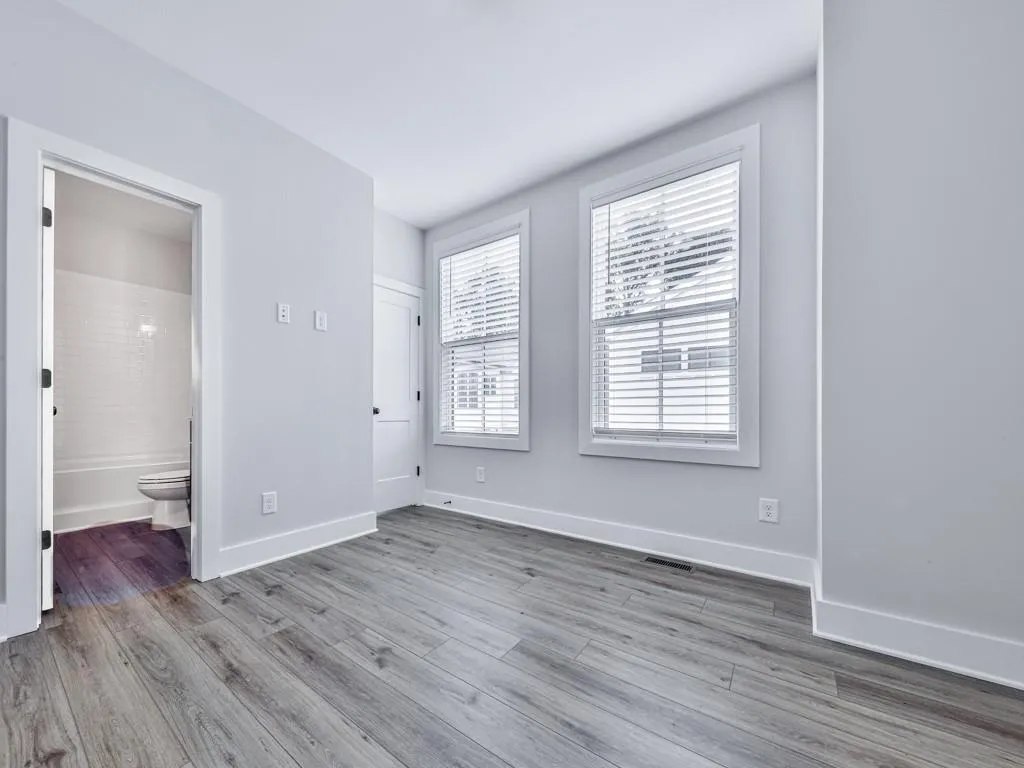 Unfurnished bedroom featuring wood-style floors and connected bathroom