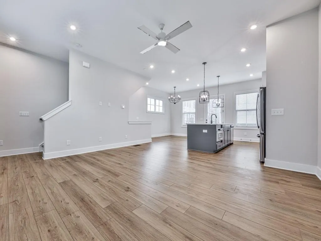 Unfurnished living room featuring recessed lighting, ceiling fan, light wood-style floors, and a chandelier