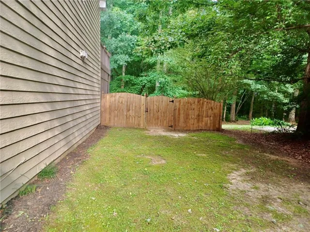 Private fenced area with a wood gate and natural tree-lined backdrop