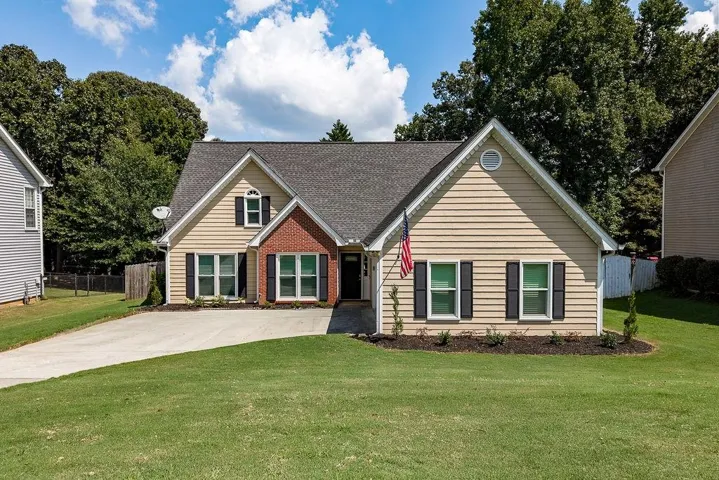 Siding exterior with brick accents, dark shingle roof, and a concrete driveway