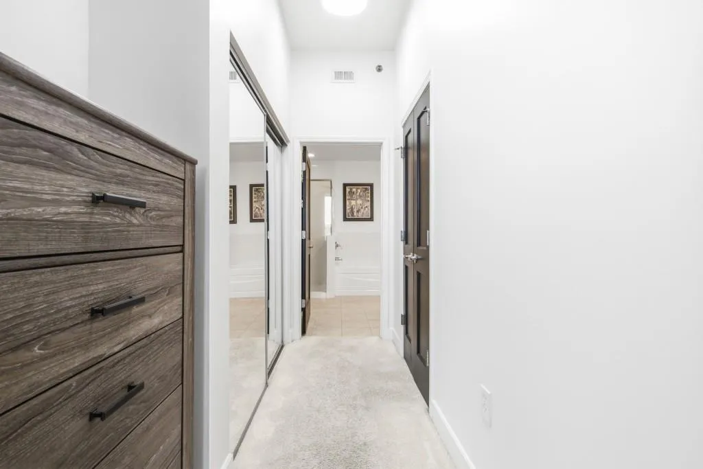 Dresser alcove and closet doors create functional hallway to primary bathroom